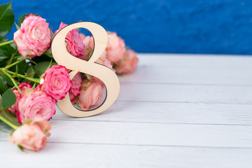 Wooden figure 8 with pink flowers on a white table. International women day. March 8