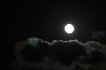 Naklejka na ściany i meble Full moon pictured against cloudy night sky