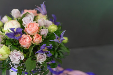 bright floral arrangement in a round box with colored ribbons on a dark gray background (color: purple, pink, green. Flowers: rose, peony)