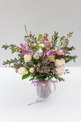 Gorgeous flower arrangement in a vase on a light background (color: white, pink, green. Flowers: rose, anemone, pistachio leaves)