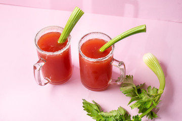 Mexican beer cocktail called michelada with celery on pink background