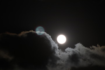 Fototapeta na wymiar Full moon pictured against cloudy night sky