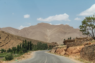 Empty road in southern Morocco with blue skies and mountains in the background