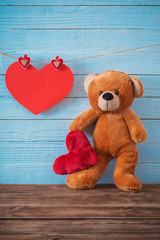 Teddy bear with red heart on old wooden background. Valentine's