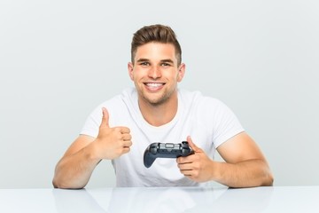 Young man holding a game controller smiling and raising thumb up