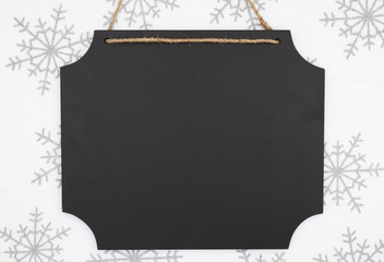 Blank hanging chalkboard with white and gray snowflake background © Karen Roach