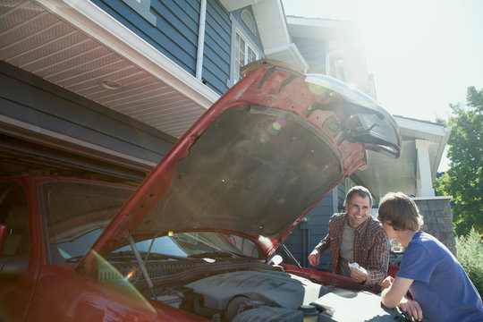Father and son repairing car in driveway