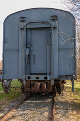 Fototapeta na wymiar Back door of an old abandoned blue gray railroad train car showing the coupling hook and track