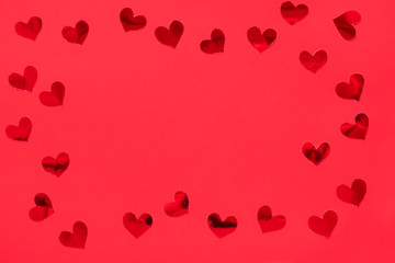Frame made of red shiny hearts on red background