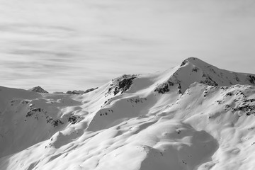 Snowy off piste ski slope at high winter mountains and sunlit cloudy sky