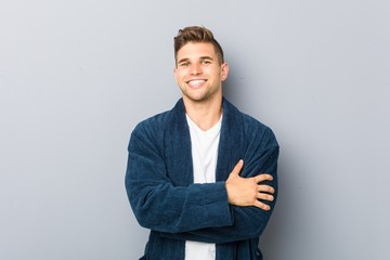 Young caucasian man wearing pajama who feels confident, crossing arms with determination.
