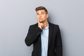 Young handsome caucasian man looking sideways with doubtful and skeptical expression.