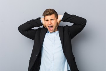 Young handsome caucasian man covering ears with hands trying not to hear too loud sound.