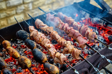 Barbecue. Pieces of meat and potatoes are fried\I on skewers with burning coals.