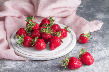 Ripe strawberries on a white board on a gray concrete background