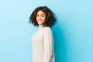 Fototapeta premium Young african american curly hair woman looks aside smiling, cheerful and pleasant.