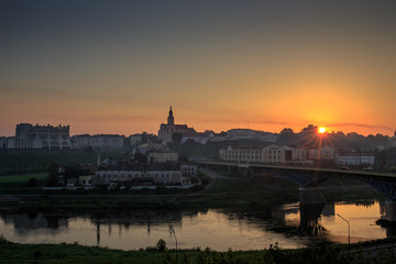 Fototapeta premium Grodno. City center at dawn. A light haze and a red disc of the sun over the roofs of houses.