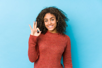 Young african american curly hair woman cheerful and confident showing ok gesture.