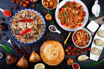 The concept of oriental cuisine. Assorted Uzbek food set, pilaf, samsa, lagman, manta, shurpa Uzbek restaurant concept, Uzbek food. Homemade Uzbek pilaf or plov from lamb served in cast iron cookware