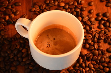 cup of coffee next to coffee grain 