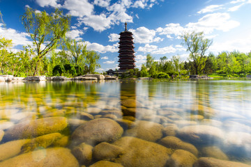 Chinese pagoda, in the foreground transparent water with stones.