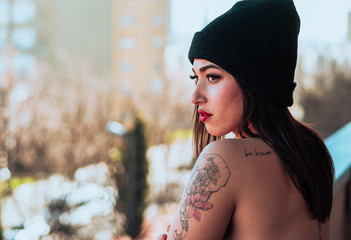 Mujer con rasgos exóticos y tatuajes mirando por un balcón