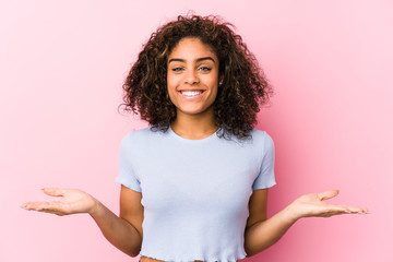 Young african american woman against a pink background showing a welcome expression.