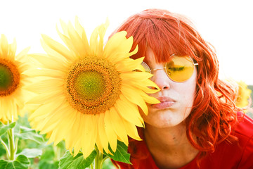 Fototapeta premium Lovely redhead woman enjoying the day in a field o sunflowers