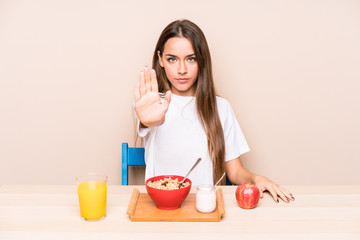 Young caucasian woman having a breakfast isolated standing with outstretched hand showing stop sign, preventing you.