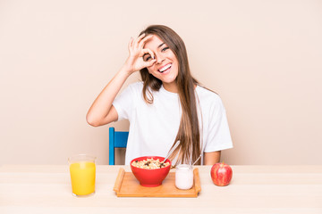 Young caucasian woman having a breakfast isolated excited keeping ok gesture on eye.