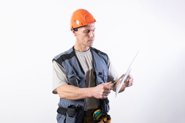 The builder is cleaning a spatula. In work clothes and hard hat. On a light gray background.