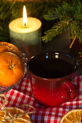 New year's tea. A fragrant green candle illuminates a red Cup of tea, a fir branch, and tangerines.