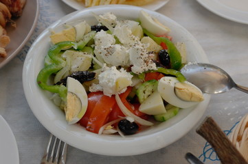 Cretan salad with vegetables, cheese, olives and eggs on a white plate