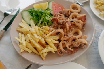 fried potatoes with seafood on a white plate