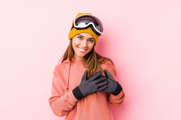 Young caucasian woman wearing a ski clothes isolated laughing keeping hands on heart, concept of happiness.