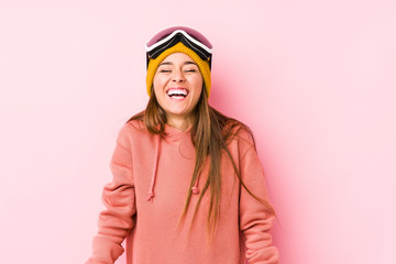 Young caucasian woman wearing a ski clothes isolated laughs and closes eyes, feels relaxed and happy.