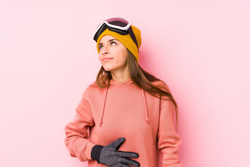 Young caucasian woman wearing a ski clothes isolated touches tummy, smiles gently, eating and satisfaction concept.