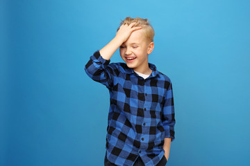 Happy child, laughing boy. Happy, smiling boy on a blue background expresses emotions through gestures.