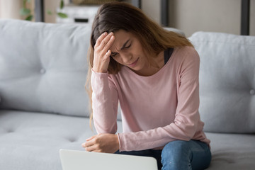 Stressed exhausted upset millennial woman suffering from sudden head ache.