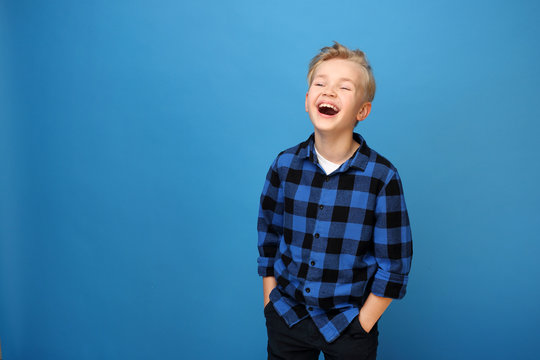 Happy child, laughing boy. Happy, smiling boy on a blue background expresses emotions through gestures.