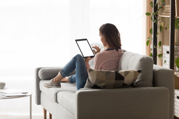 Young woman holding tablet with blank screen back view.