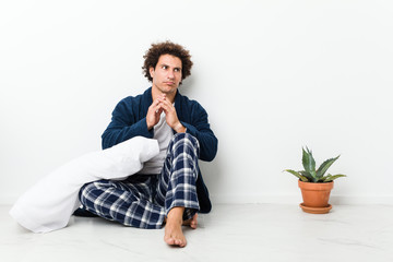 Mature man wearing pajama sitting on house floor making up plan in mind, setting up an idea.