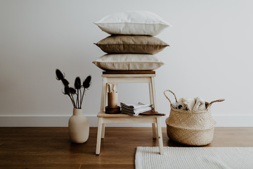 Stool with pillows, vase with dried flowers and basket with textile