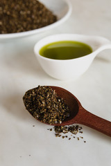 Natural hemp oil in a ceramic spoon and hemp fiber in a wooden spoon on a light background