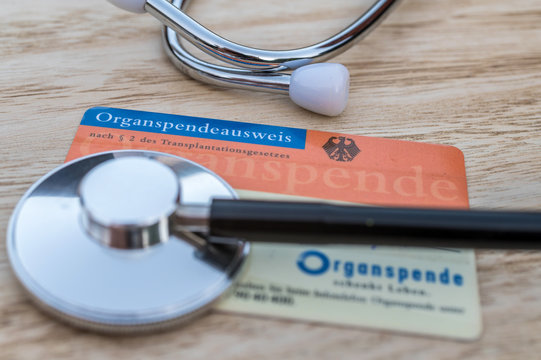 Deutscher Organspendeausweis mit einem Stethoskop vor hölzernen Hintergrund