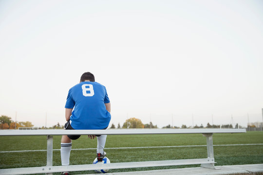 View from behind of one soccer player on bench.