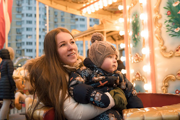 Fototapeta na wymiar Mother and child on the carousel. Vintage carousel. The winter fair. Christmas fair. Happy family.