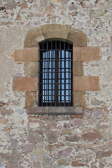 Fototapeta na wymiar Old Rough Textured Stone Wall & Large Window with Iron Bars 