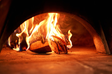 Firewood is burning, the stove is being heated. Red hot coal. Traditional wood oven in Naples restaurant, Italy. Original neapolitan pizza.