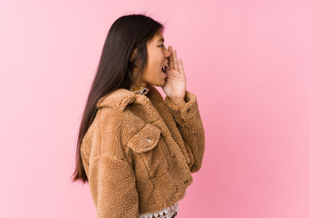 Young asian woman shouting and holding palm near opened mouth.